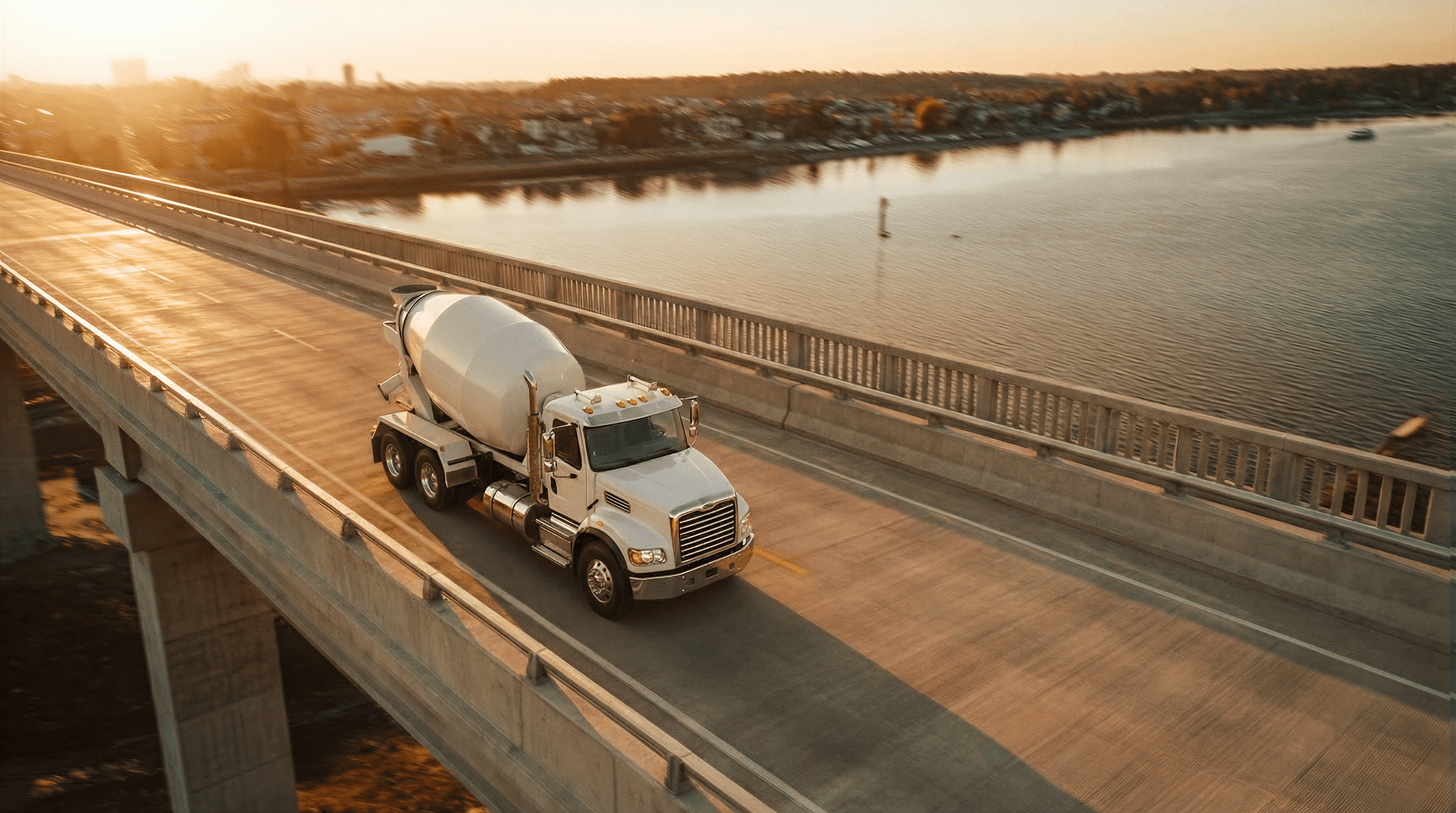 Mixer truck driving across a bridge in the sunset
